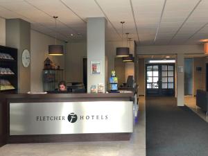 une femme assise à la réception dans le hall de l'hôtel dans l'établissement Fletcher Hotel-Restaurant Waalwijk, à Waalwijk