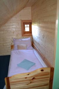 a bed in a wooden cabin with a window at Penzion U mlýna in Rejvíz