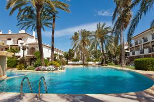 a swimming pool with palm trees and a building at Bahia Azul VyB in Denia