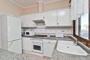 a kitchen with white cabinets and a sink at Bahia Azul VyB in Denia