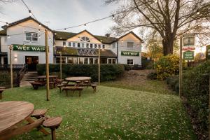 a pub with tables and benches in front of a building at Wee Waif by Greene King Inns in Reading