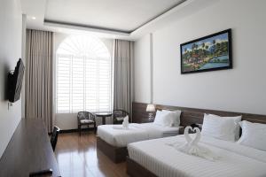 a hotel room with two beds and a table at Sun Horizon Hotel - Phnom Penh in Phnom Penh