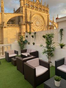 a rooftop patio with chairs and a building at Catedral Boutique in Seville