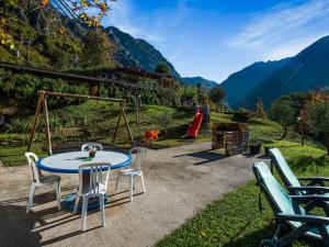 マローネにあるBeautiful chalet with Swimming Pool in Lombardyのパティオ(テーブル、椅子、プレイグラウンド付)