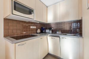 eine Küche mit weißen Schränken und einer Mikrowelle in der Unterkunft Residence La Foret - maeva Home in Arâches-la-Frasse