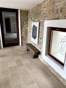 Habitación con pared de piedra, banco y ventana. en Hotel Casa Fumanal, en Abizanda