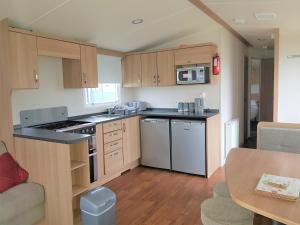 a kitchen with wooden cabinets and stainless steel appliances at 720 Holiday Resort Unity, Brean in Brean