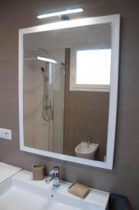 un bagno con un grande specchio sopra un lavandino di La Torre GMA Tourism a Torre Lapillo