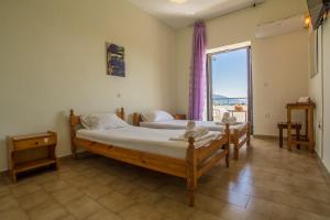 two beds in a room with a large window at Aggeliki apartments Dassia By Hotelius in Kato Korakiana +17 photos