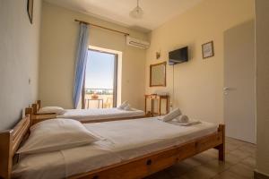two beds in a room with a window at Aggeliki apartments Dassia By Hotelius in Kato Korakiana