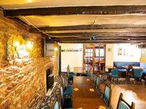 a restaurant with wooden tables and chairs and a stone wall at Longforgan Coaching Inn in Dundee