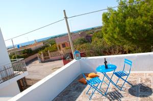 een blauwe tafel en stoelen op een balkon met uitzicht op de oceaan bij Punta Prosciutto GMA Tourism in Porto Cesareo