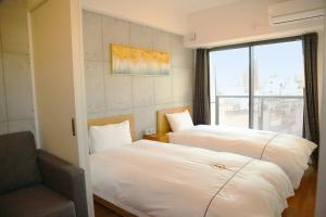 um quarto com duas camas e uma cadeira e uma janela em Yoshitsuki kaku - Yoshitsuki Apart Hotel em Tóquio