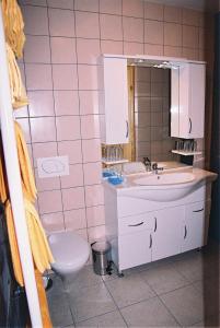 a pink tiled bathroom with a sink and a toilet at Guest House Čater in Laško