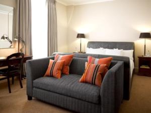 a living room with a blue couch with orange pillows at The Angel Hotel in Abergavenny