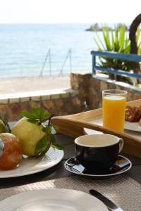 a table with plates of food and a glass of orange juice at Haraki Blue Pearl Luxury studio in Haraki