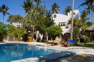 a woman sitting on a chair next to a swimming pool at Laguna Palace Zanzibar in Michamvi