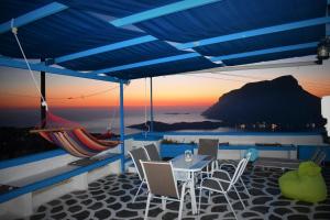 een patio met een tafel en stoelen en een hangmat bij Villa Marzi Kalymnos in Kalymnos