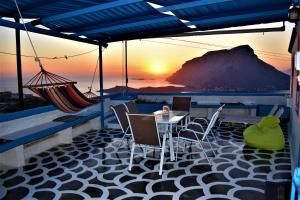 a patio with a table and chairs and a sunset at Villa Marzi Kalymnos in Kalymnos