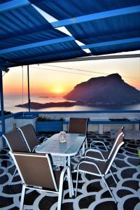 een tafel en stoelen op een terras met zonsondergang bij Villa Marzi Kalymnos in Kalymnos