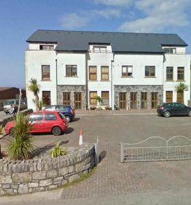 een groot wit gebouw met auto's geparkeerd op een parkeerplaats bij Surfers Getaway - Room Staycation in Sligo