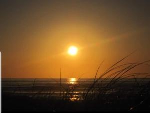 a sunset on a beach with the ocean and grass at Surfers Getaway - Room Staycation in Sligo