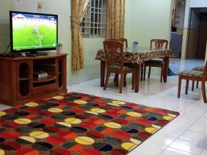 uma sala de estar com televisão e uma mesa com cadeiras em Muslim Homestay Ustaz 2 em Taiping