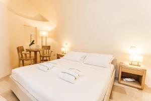 a white bed in a room with a table at La Sommità Relais & Chateaux in Ostuni