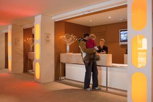 a man holding a child in front of a counter at Residence La Foret - maeva Home in Arâches-la-Frasse