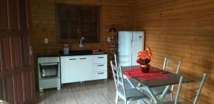 a kitchen with a table and a white refrigerator at CHALÉS DO VÔ LÉRIO/TORRES-RS in Torres