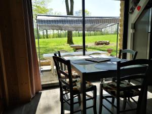a table and chairs in a room with a window at Chalet aux 3 Ours , Kota-Grill, sauna in Le Val-dʼAjol