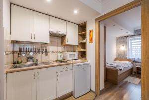 a kitchen with white cabinets and a sink and a bed at Ośrodek Wypoczynkowy Cypel in Polańczyk +54 photos