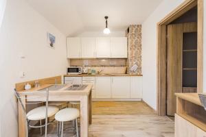 a kitchen with white cabinets and a table with stools at Ośrodek Wypoczynkowy Cypel in Polańczyk