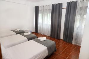 Duas camas num quarto com cortinas e pisos em azulejo em lisbon Home host em Lisboa