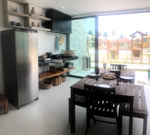 eine Küche mit einem Tisch und einem Kühlschrank aus Edelstahl in der Unterkunft Casa Morada do Toque in São Miguel dos Milagres