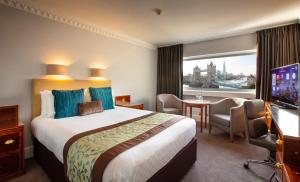 Cette chambre comprend un grand lit et une fenêtre. dans l'établissement The Tower Hotel, London, à Londres