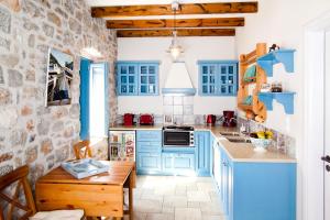 a kitchen with blue cabinets and a stone wall at Petra Boutique Homes in Aryinónda