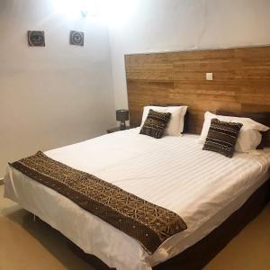 ein Schlafzimmer mit einem großen Bett mit weißer Bettwäsche und Kissen in der Unterkunft Harmony Resort Boutique Hotel in Banjul