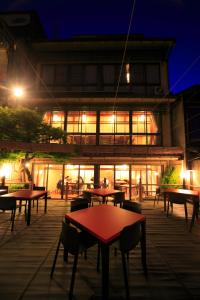 un bâtiment avec des tables et des chaises devant lui la nuit dans l'établissement Tazuru, à Kyoto