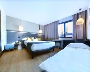 um quarto de hotel com duas camas e um sofá em Hôtel Le Roosevelt Lyon em Lyon