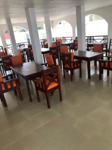 jadalnia z drewnianymi stołami i krzesłami w obiekcie Harmony Resort Boutique Hotel w mieście Bandżul