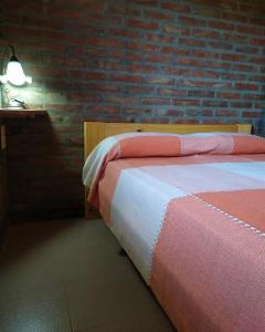 a bedroom with a bed and a brick wall at Cabañas Müller in Huechulafquen Lake