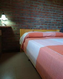 1 dormitorio con cama y pared de ladrillo en Cabañas Müller en Lago Huechulafquen