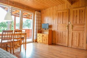 een eetkamer met een tafel en een televisie bij Domki Letniskowe Pod Orzechem Dziwnówek-Wrzosowo in Wrzosowo