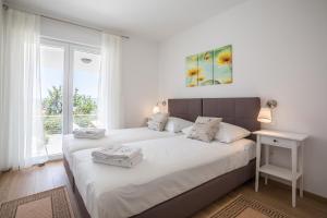 una camera con due letti con lenzuola bianche e una finestra di Villa Blanka Bol save 15 percent on Split-villas com a Bol