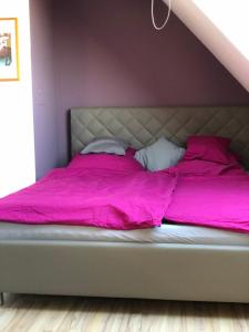 ein Bett mit rosa Bettwäsche und Kissen in einem Schlafzimmer in der Unterkunft Einzel-Apartment Düsseldorf Oberkassel in Düsseldorf