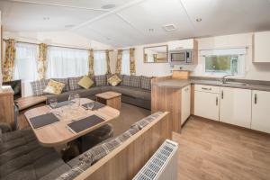 a kitchen and living room with a table and a couch at Widemouth Bay Caravan Park in Bude