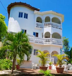 a large white building with a balcony and palm trees at Annie's White House on The Hill in Negril