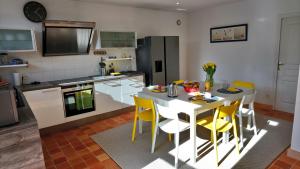 een keuken met een witte tafel en gele stoelen bij Maison familiale-Surf House, plage de Sainte Barbe in Plouharnel