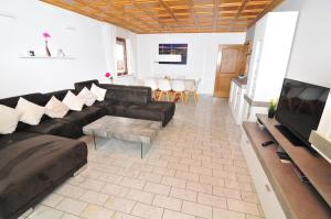 ein Wohnzimmer mit einem schwarzen Sofa und einem TV in der Unterkunft Haus Rheinterrasse in Koblenz